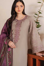 A woman models a traditional three-piece salwar kameez suit. The set features a light taupe-beige kameez long-sleeve shirt with pink and green floral embroidery on the neckline and cuffs, paired with a deep purple dupatta decorated with pink floral patterns and a green border.