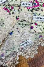 Fabric with floral patterns and lace details, labeled 'SLEEVES', 'TROUSER', and 'DAMAN' on a wooden surface.