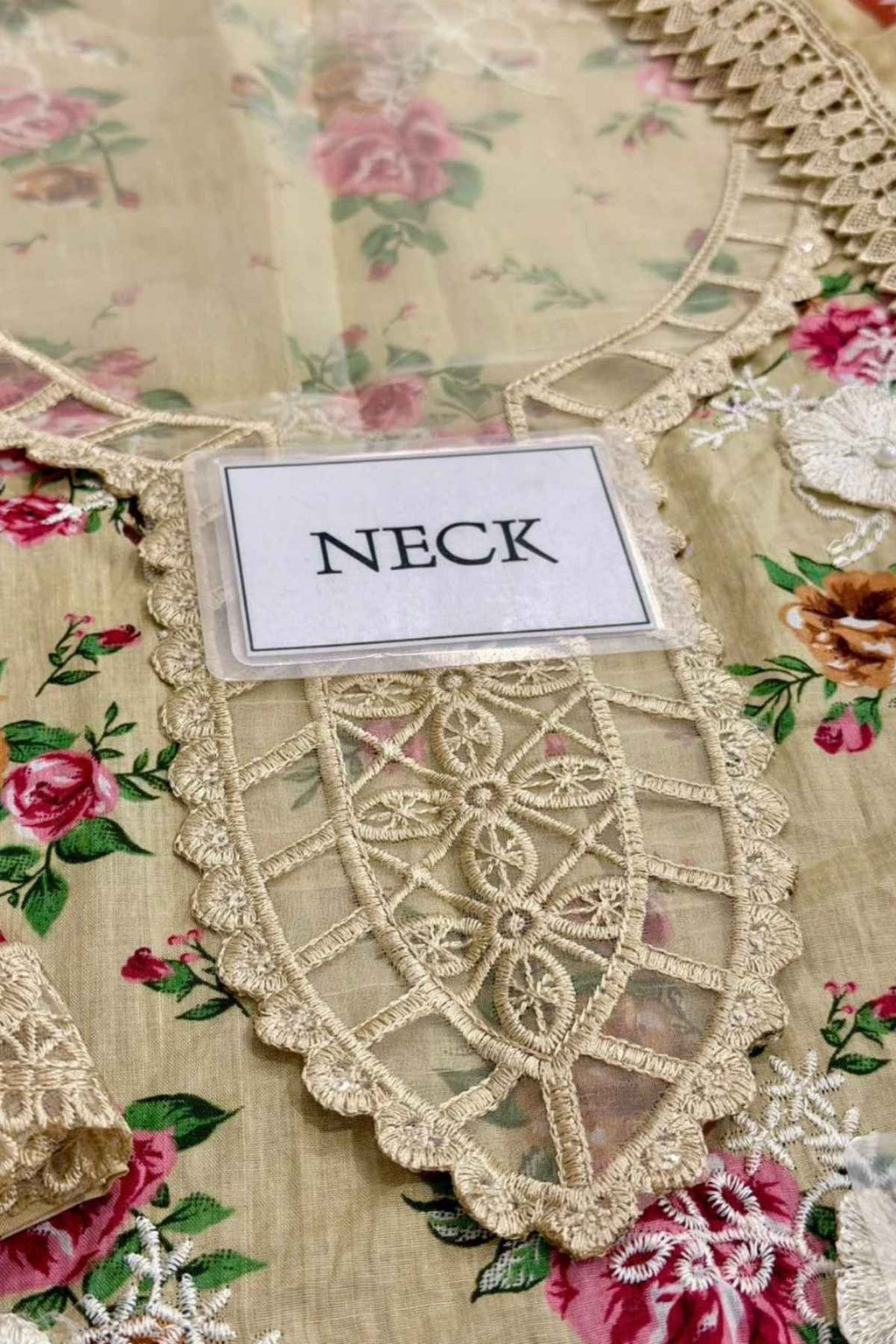 Decorative lace fabric with a card labeled 'NECK' on a floral background