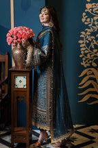 Woman in traditional blue and gold outfit holding pink flowers against a decorative wall.

Details