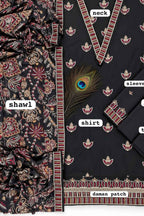 Black cotton fabric suit material set featuring a printed shirt, matching neck and sleeve panels, a patterned shawl, and a decorative peacock feather accent on a white background with labels.