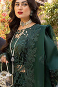 Woman wearing a green embroidered outfit with jewelry against a blurred natural background