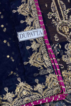 A close-up of a navy blue dupatta featuring intricate gold zari embroidery and a vibrant magenta border, with a white label reading 'DUPATTA' stitched on it.