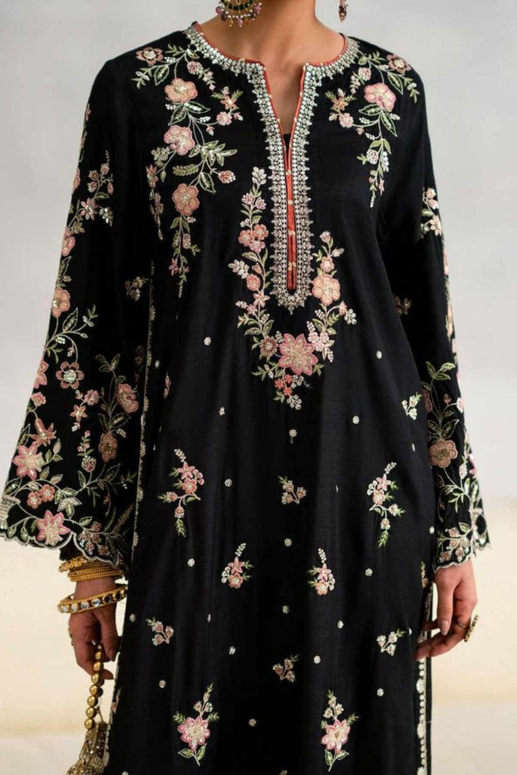 A black long-sleeve kurta featuring intricate floral embroidery in pink, green, and white, with a silver embellished V-neckline and a red accent thread down the center.