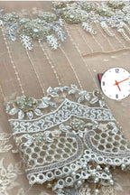 Decorative fabric with intricate silver embroidery and a clock in the corner.