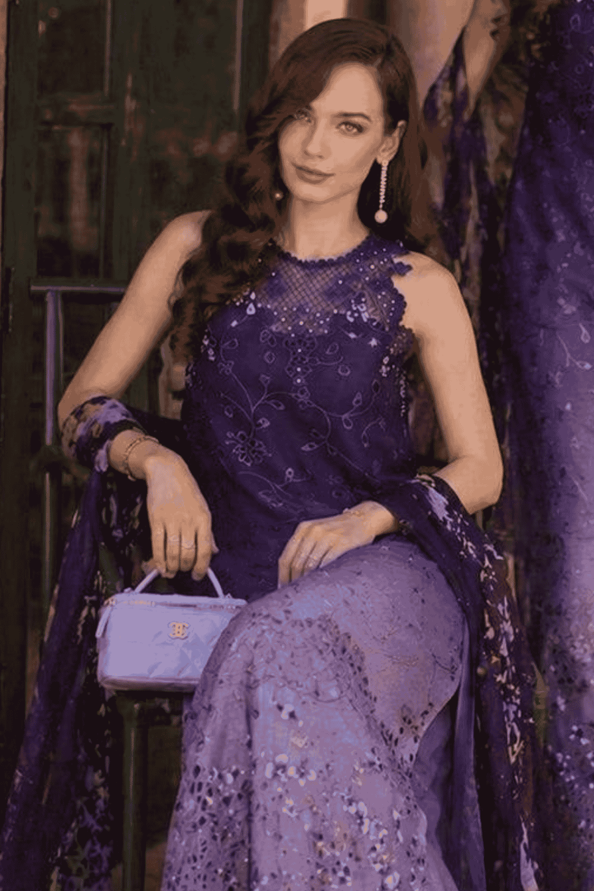 Woman in a purple dress holding a matching handbag in an elegant setting.