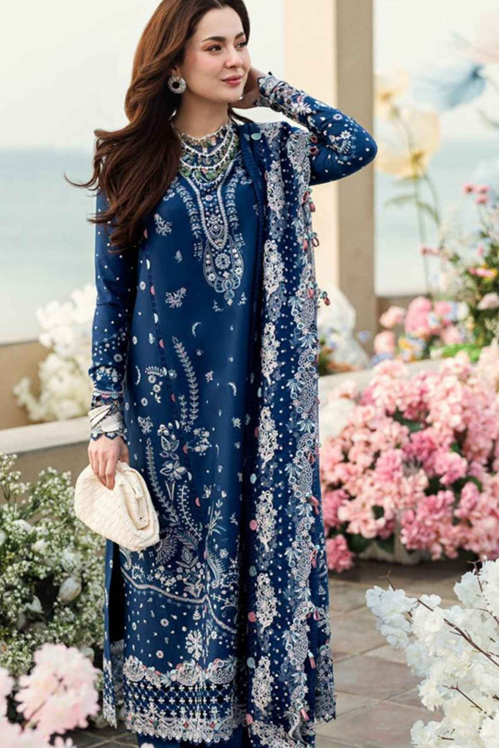 Woman in a blue embroidered dress standing among flowers