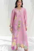 A woman models a light pink long kaftan dress with colorful floral and bird embroidery in shades of yellow, green, and purple, set against a white draped background.