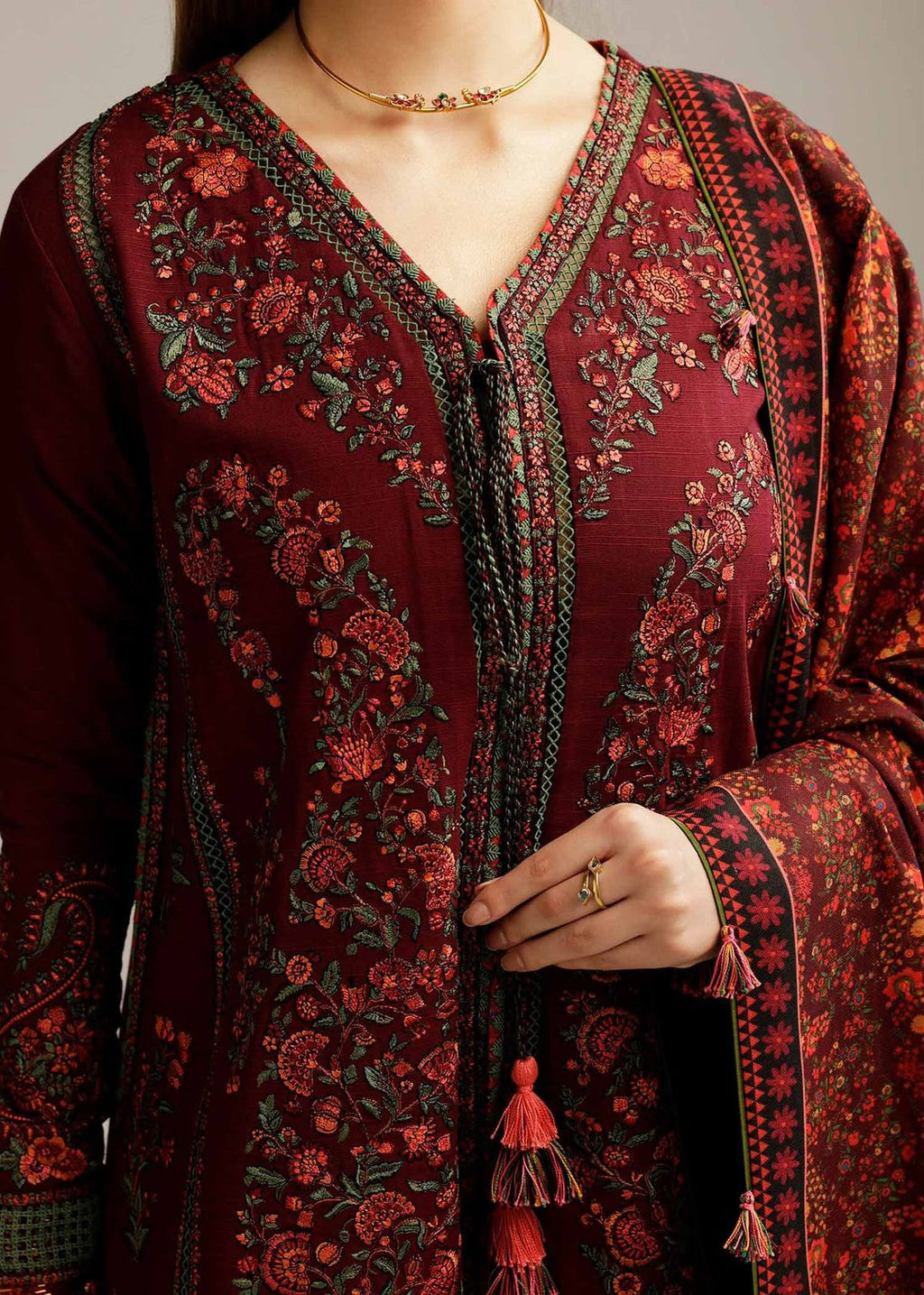 Close-up of a person wearing a burgundy embroidered traditional outfit with intricate patterns.