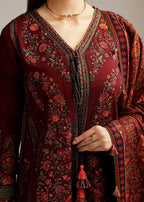 Close-up of a person wearing a burgundy embroidered traditional outfit with intricate patterns.