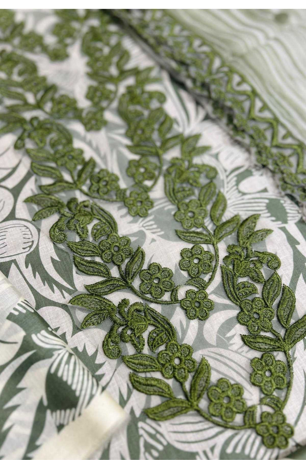 Green floral embroidery on a textured fabric background