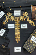 Black embroidered kurta laid flat with gold floral embroidery around the neckline and down the front placket. A matching black-and-gold silk trouser is partially visible at the lower right.