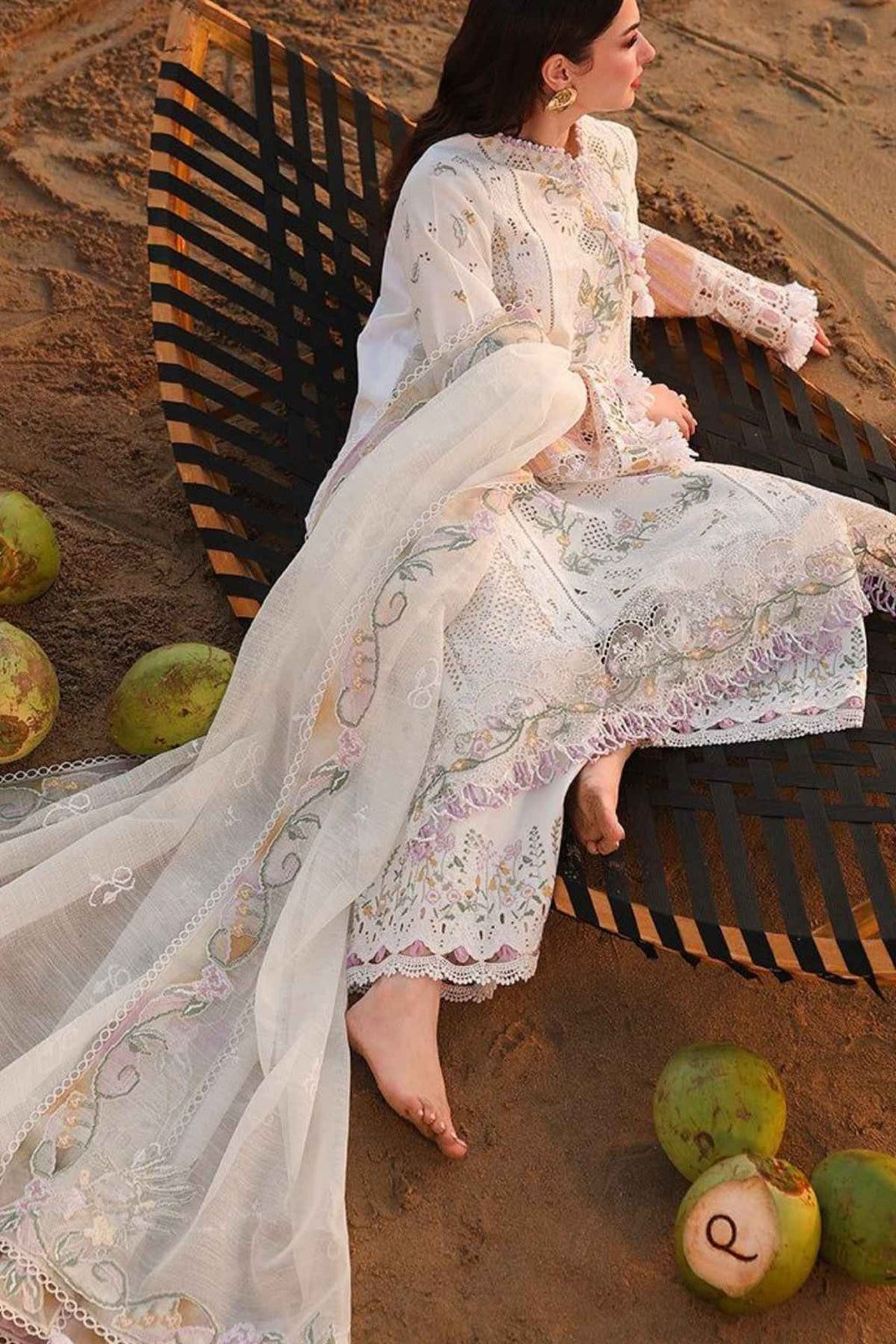 Woman in a floral dress sitting on a bench with fruits on the ground.