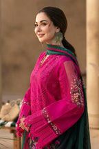 Woman wearing a pink and green traditional outfit with intricate designs.